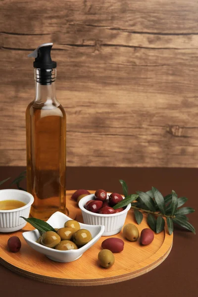 Oil, olives and tree twig on brown table