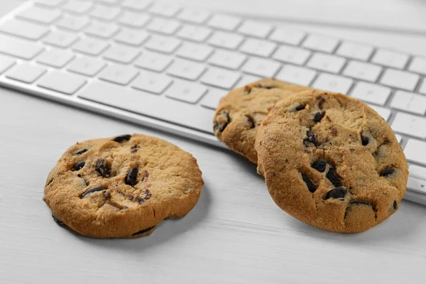 白色木制桌子上的巧克力曲奇饼和键盘 — 图库照片