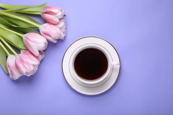 stock image Cup of coffee and beautiful tulips on light purple background, flat lay