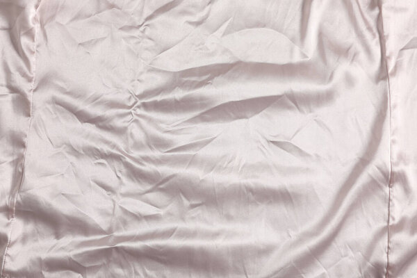 Crumpled light pink fabric as background, top view