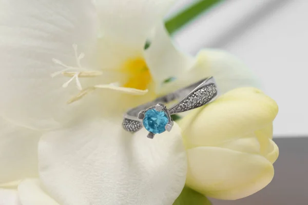 Beautiful ring with light blue gemstone on flower, closeup. Luxury jewelry