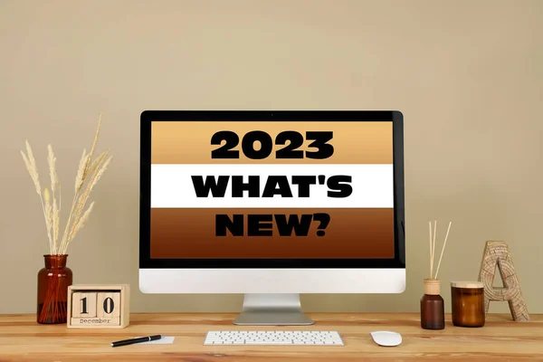 Future trends. 2023 What\'s New? text on computer monitor. Workplace with wooden table