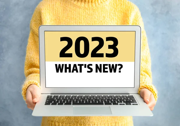 Future trends. 2023 What's New? text on laptop display. Woman holding device, closeup