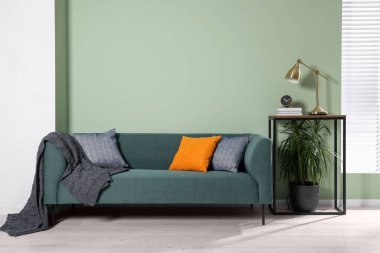 Konsol masasının yanında rahat kanepe, battaniye ve yastıklar bulunan şık bir iç mekan.