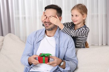 Sevimli küçük kız, babasına hediyesini evde sunuyor.