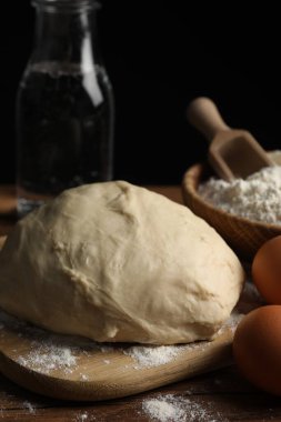 Sodalı çörekler pişiriyorum. Hamur ve malzemeler ahşap masada, yakın plan.