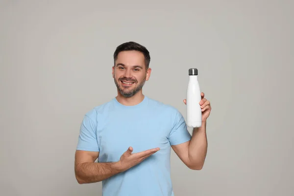 Ευτυχισμένος Άνθρωπος Δείχνει Θερμοφόρα Μπουκάλι Ανοιχτό Γκρι Φόντο — Φωτογραφία Αρχείου