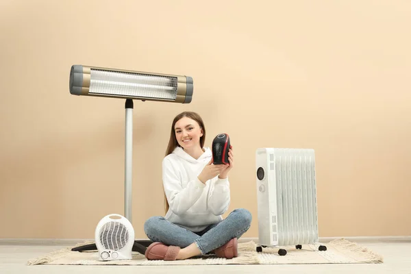 Mujer Joven Con Diferentes Calentadores Eléctricos Modernos Cerca Pared Beige —  Fotos de Stock