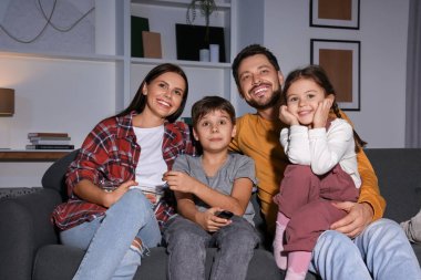 Mutlu aile akşamları evde televizyon seyrediyor.
