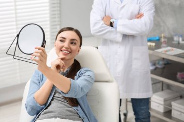 Yeni diş implantlarına bakan genç bir kadın.