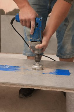 Worker making socket hole in tile indoors, closeup