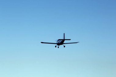 Modern ultralight airplane flying in blue sky clipart