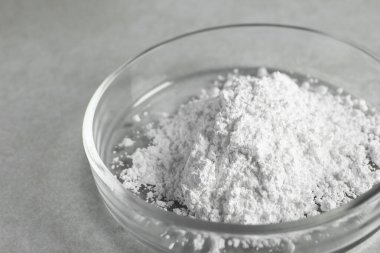 Petri dish with calcium carbonate powder on light grey table, closeup