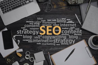 Arama motoru optimizasyonu (SEO). Kelime bulut, dizüstü bilgisayar ve kırtasiye ahşap masa, düz yatıyordu