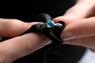 Kuyumcu, mikrofiber bezle topaz yüzüğünü temizliyor.