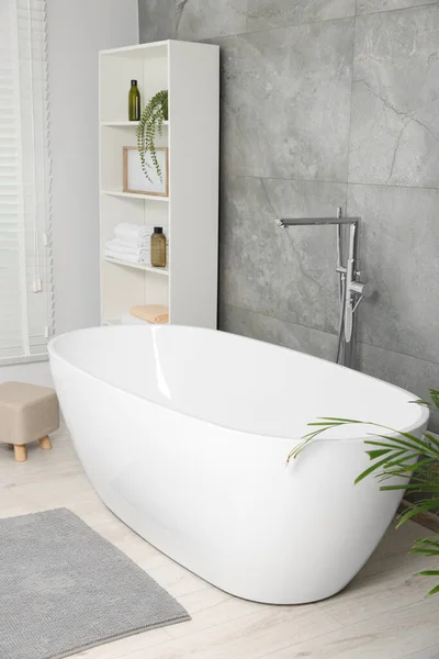 キャビネット内のセラミック浴槽 ケア製品やタオルとスタイリッシュなバスルームのインテリア — ストック写真