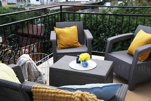 外の籐の庭の家具のオレンジ枕と黄色の菊の花 — ストック写真