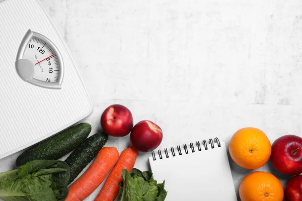 Scales, notebook, fresh fruits and vegetables on light gray textured table, flat lay with space for text. Low glycemic index diet