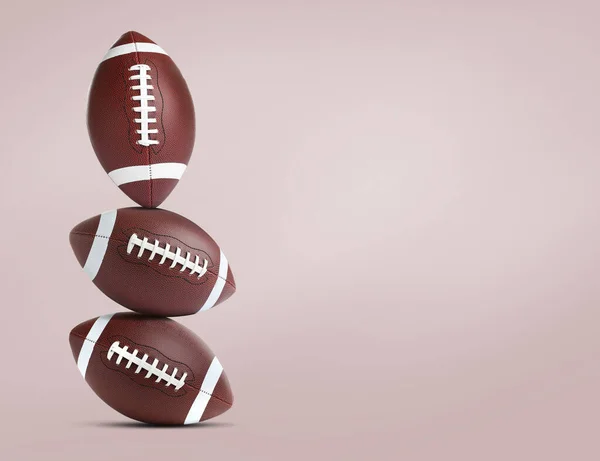 Stack of American football balls on pale pink background. Space for text