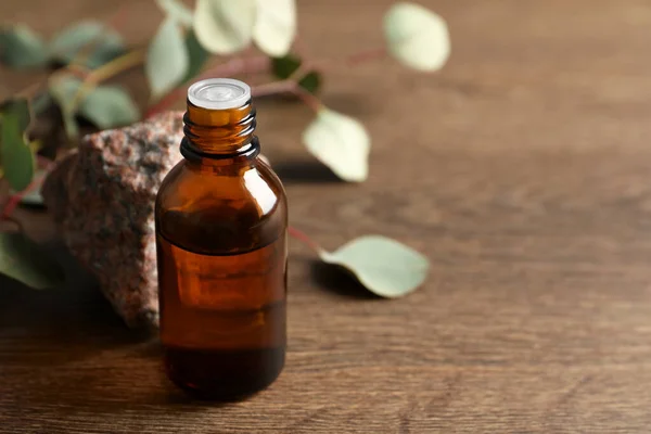 Eine Flasche Ätherisches Eukalyptusöl Stein Und Blätter Auf Dem Holztisch — Stockfoto
