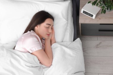 Güzel, genç bir kadın yumuşak bir yatakta uyuyor.