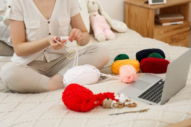 Woman learning to knit with online course at home, closeup. Handicraft hobby