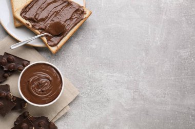 Lezzetli bir kahvaltı. Gri desenli masada servis edilen tatlı ezmeli ve çikolata parçalı düz kompozisyon. Metin için boşluk