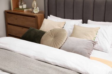 Yastıklı rahat bir yatak ve odasındaki tahta çekmecelerin üzerinde farklı bir dekor. Şık iç mekan