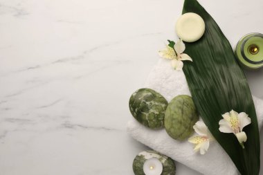 Flat lay composition with spa products and flowers on white marble table. Space for text