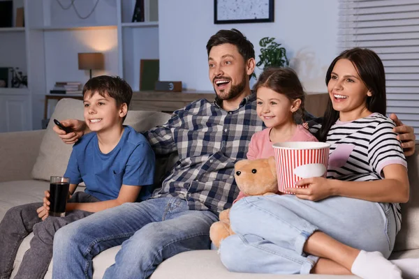 幸せな家族は夕方に自宅で映画を見ている お父さんはリモコンでテレビチャンネルを変える — ストック写真
