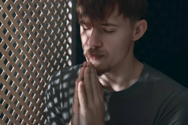 Człowiek Modlący Się Podczas Spowiedzi Przy Drewnianym Oknie Kabinie — Zdjęcie stockowe