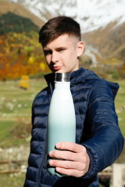 stock image Boy holding thermo bottle with drink in mountains, focus on hand