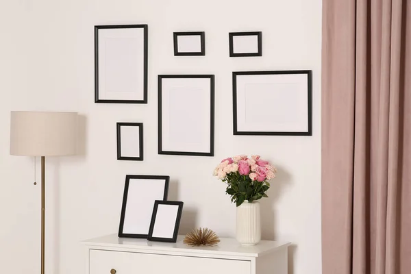 白色的墙壁上挂着空的框架 抽屉里挂着鲜花 — 图库照片