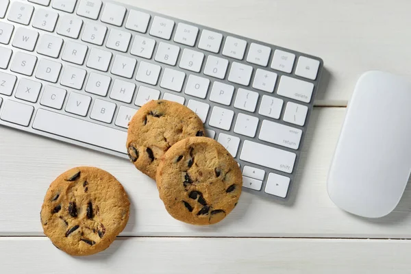 白い木製のテーブルの上にチョコレートチップクッキー キーボードとコンピュータマウス フラットレイ — ストック写真