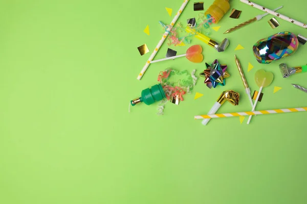 Party poppers with colorful streamers, blowers and festive decor on light green background, flat lay. Space for text