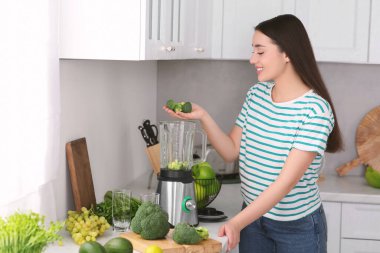 Mutfakta smoothie için blender 'a brokoli ekleyen kadın