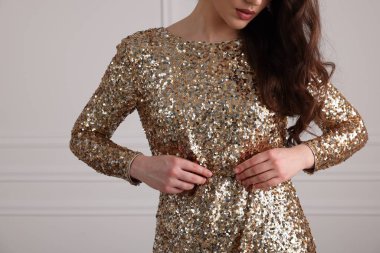 Beyaz duvarın yanında zarif elbiseli güzel bir kadın, yakın plan. Metin için boşluk