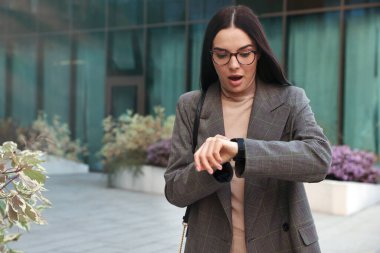Emotional woman checking time on watch outdoors. Being late concept