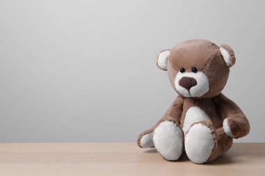 Işık duvarının yanındaki ahşap masada şirin bir oyuncak ayı, mesaj için yer var.