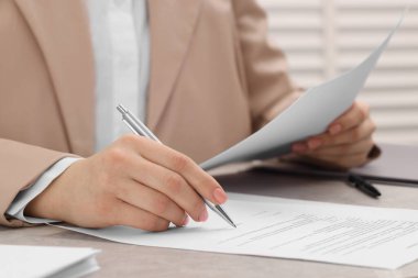 Woman signing document at table, closeup view
