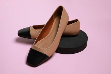 Pair of new stylish square toe ballet flats on pale pink background