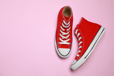 Pembe arka planda yeni bir çift şık kırmızı spor ayakkabı, düz. Metin için boşluk