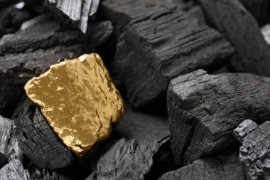 Parlak altın külçeleri kömürlerin üzerinde, yakın çekim manzarası