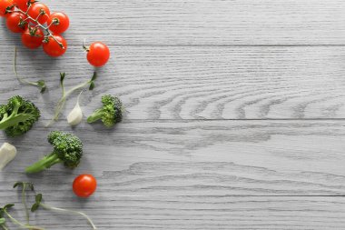 Yemek fotoğrafçılığı. Taze vişneli domates, brokoli, sarımsak ve mikroyeşil ahşap masa üzerinde, düzlük yazı için yer var.