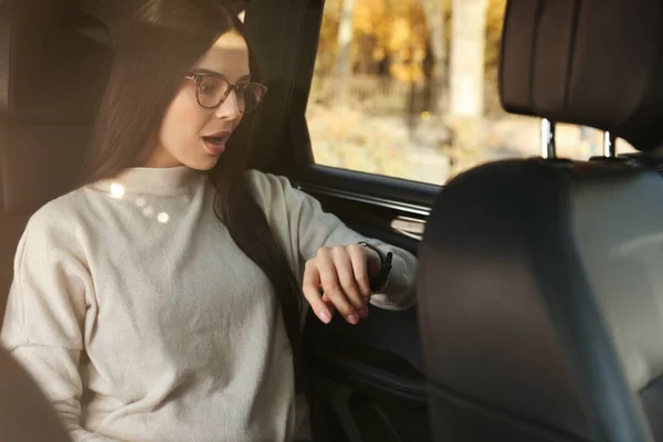情绪化的女人坐在车上看时间 迟到的概念 — 图库照片