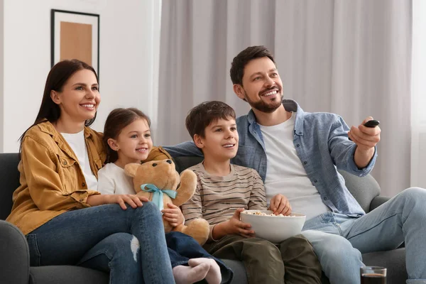 家庭でテレビを見て幸せな家族 お父さん遠隔操作でチャンネルを変える — ストック写真