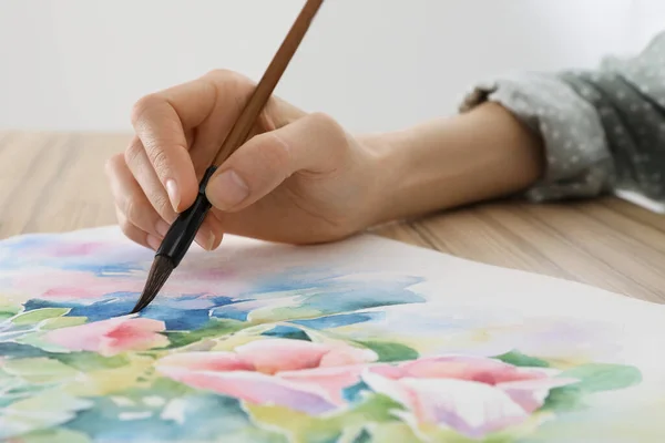 女人在木制桌旁画水彩画花 创意艺术品 — 图库照片
