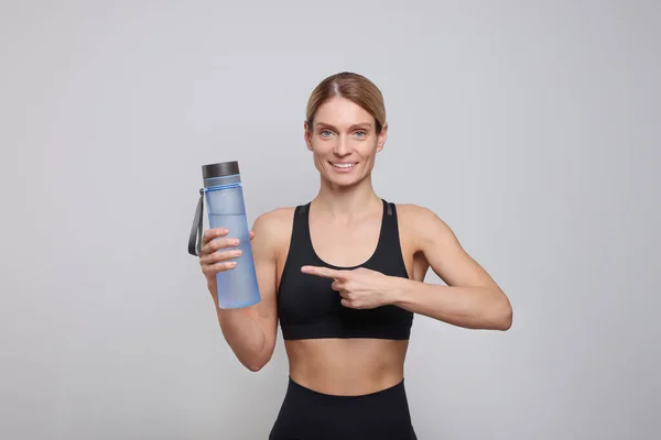 ライトグレーの背景に水のボトルを持つスポーツ女性 — ストック写真