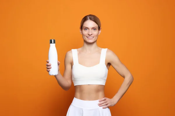 Sportlerin Mit Thermoflasche Auf Orangefarbenem Hintergrund — Stockfoto