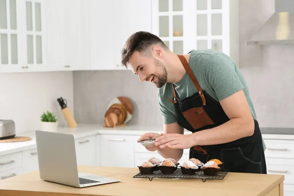Man Díszítő Muffinok Porcukorral Miközben Néz Online Főzés Természetesen Laptopon — Stock Fotó